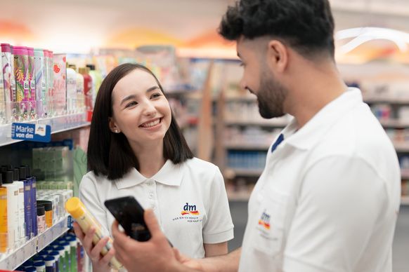 Zwei dm-Lernlinge prüfen den Artikelbestand mit Smartphone