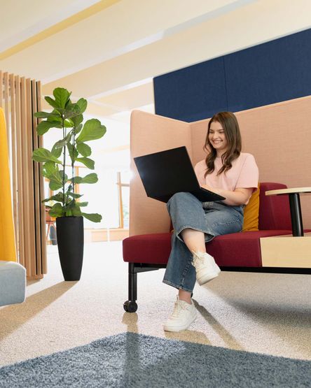 Junge Frau arbeitet am Laptop in der Sitzecke am dm-Unternehmenssitz