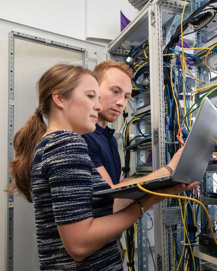 Angehender Fachinformatiker mit Ausbilderin mit Rechner im Technikraum