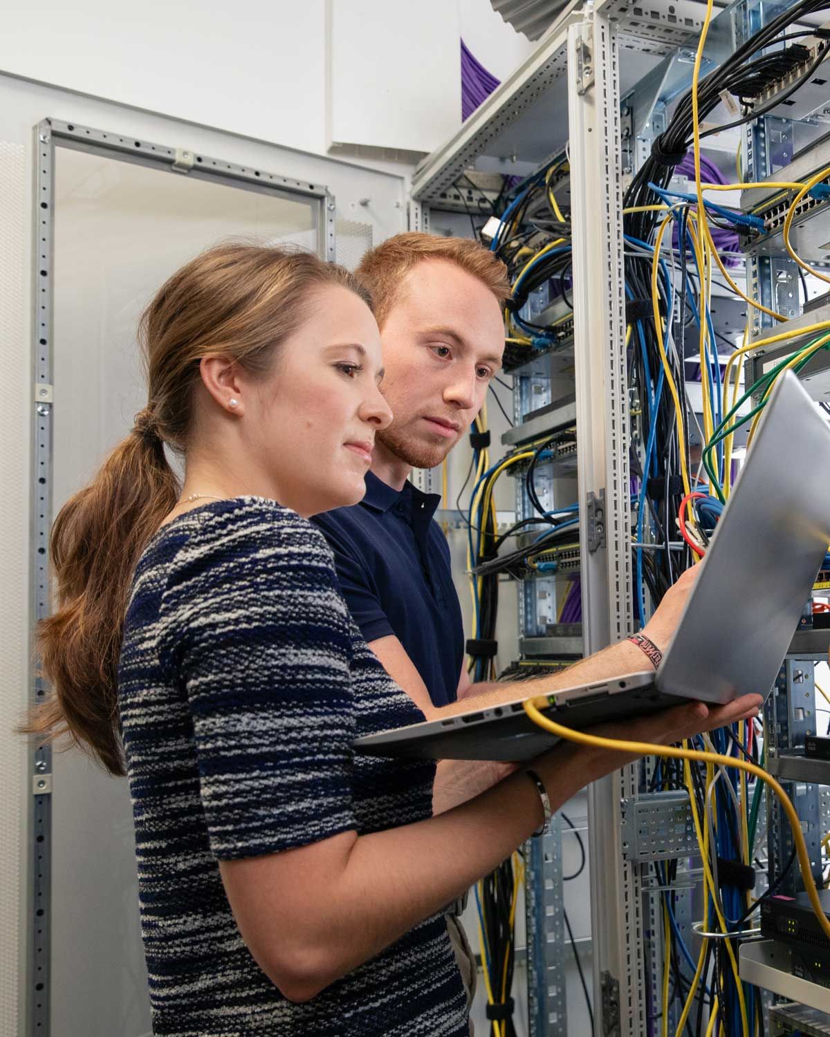 Angehender Fachinformatiker mit Ausbilderin mit Rechner im Technikraum