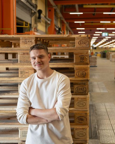 Junger Man steht vor Euro-Paletten im Warenausgang eines dm-Logistikzentrums