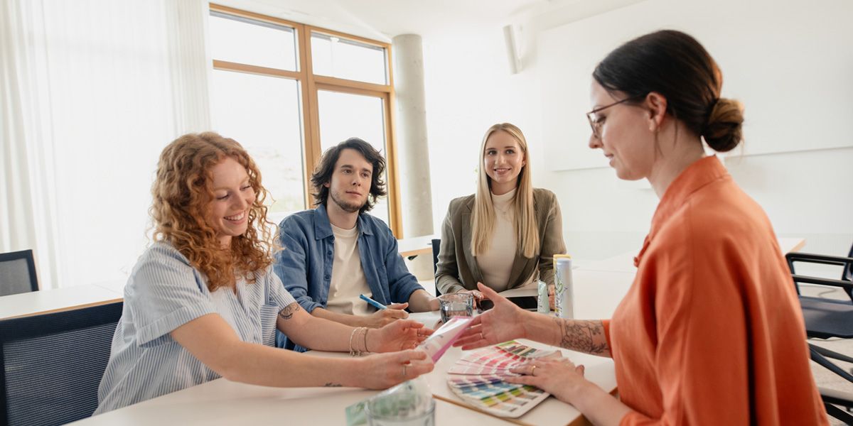 drei dm-Studierende im Gespräch mit Ausbilderin zu Produktverpackung und Farbgestaltung