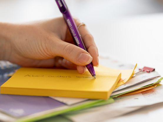 Frau schreibt auf gelben Post-its mit lila Kuli