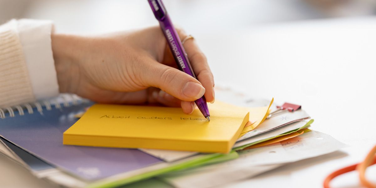 Frau schreibt auf gelben Post-its mit lila Kuli