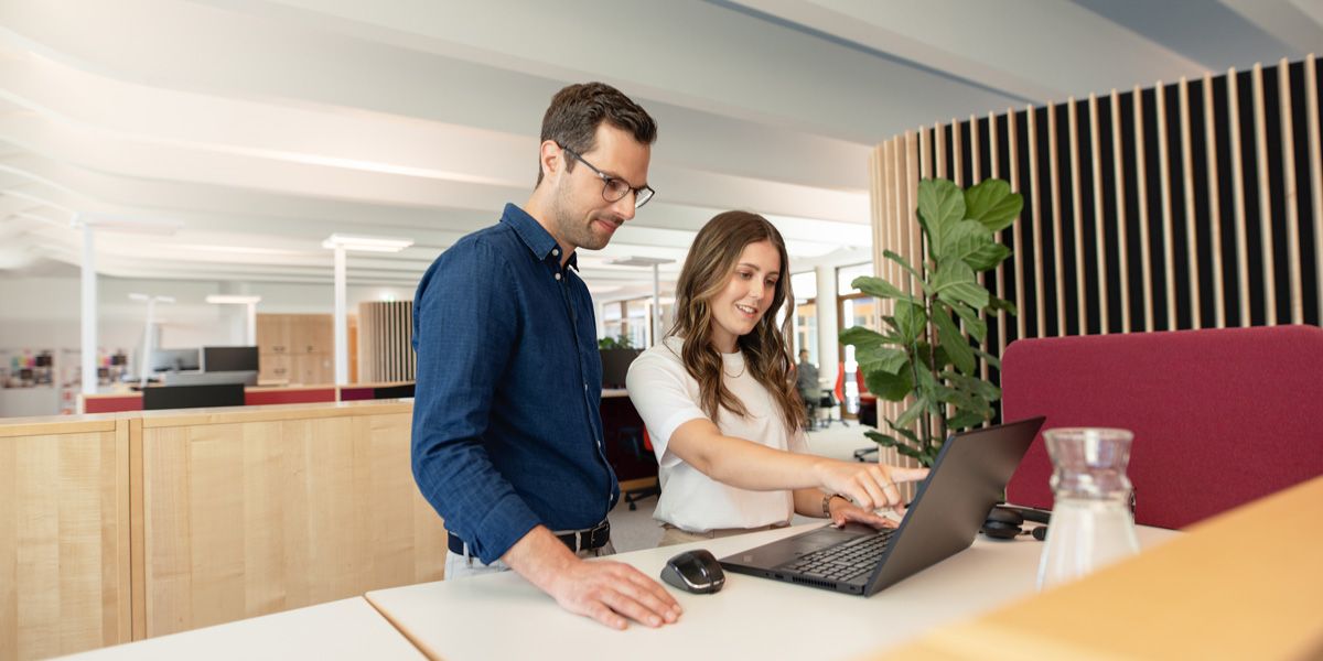 Angehende Personaldienstleistungskauffrau mit Ausbilder vor Laptop im dm-Unternehmenssitz