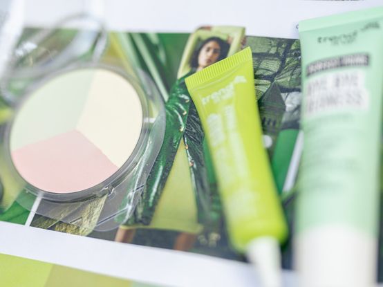 Drei Kosmetikprodukte auf grünem Flyer