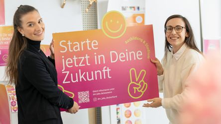 Zwei dm-Mitarbeitende mit Werbeplakat mit Aufschrift "Starte jetzt in Deine Zukunft"
