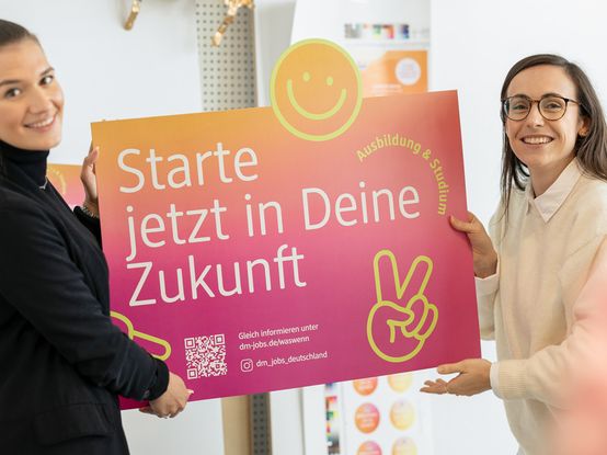 Zwei dm-Mitarbeitende mit Werbeplakat mit Aufschrift "Starte jetzt in Deine Zukunft"
