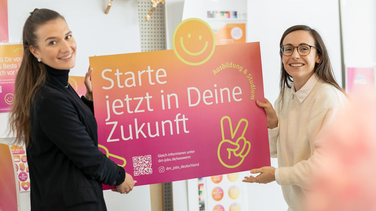Zwei dm-Mitarbeitende mit Werbeplakat mit Aufschrift "Starte jetzt in Deine Zukunft"