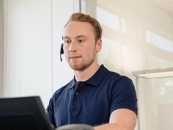Angehender Fachinformatiker mit Headset am Rechner