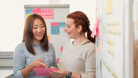 Zwei Studierende mit Post-Its vor Whiteboard