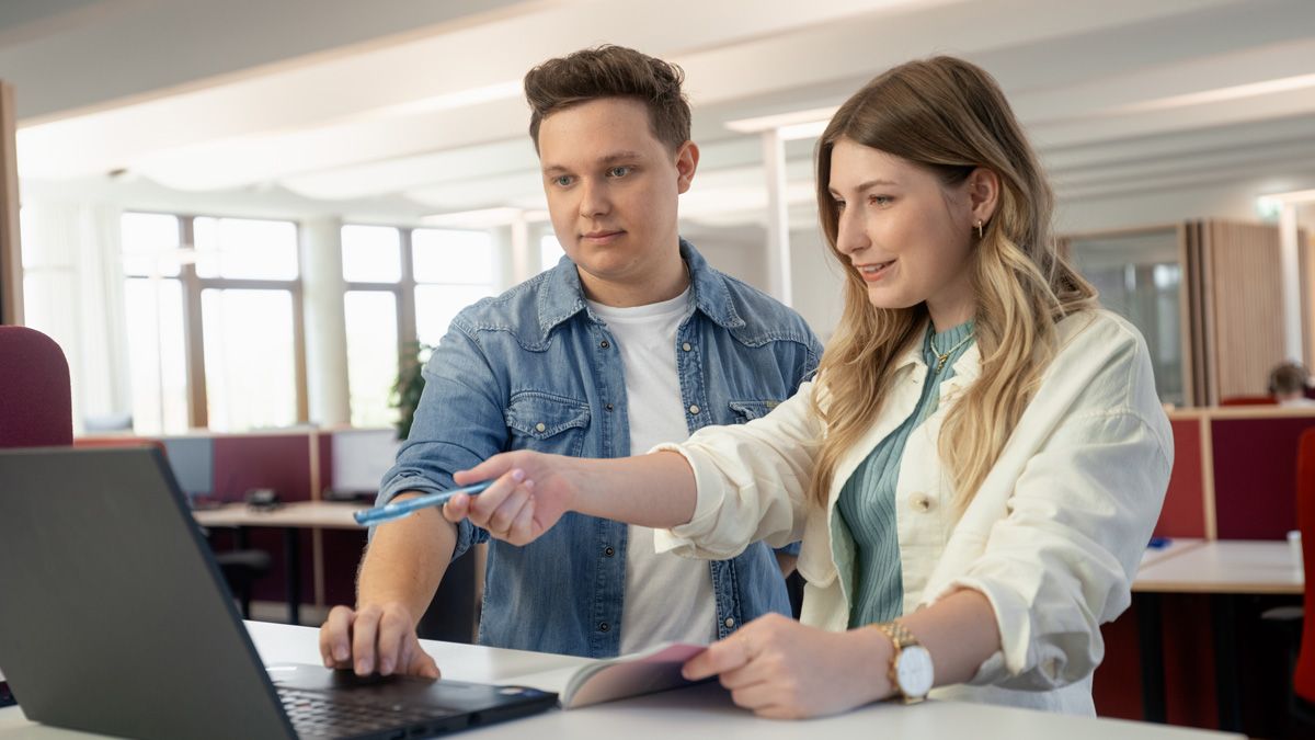 Zwei junge Menschen im Gespräch vor Laptop im dm-Unternehmenssitz