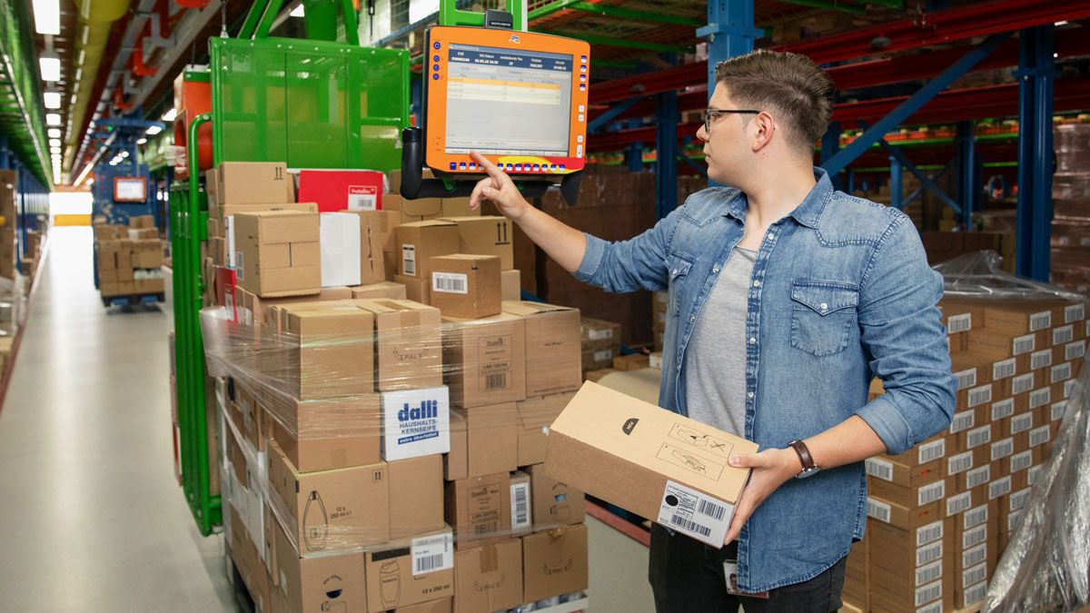Fachlagerist in Ausbildung überprüft Ware mithilfe von Elektrohängebahn