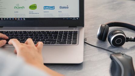 Headset, Maus und Laptop auf dem eine Person tippt