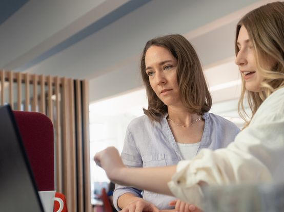 dm-Studierende in Diskussion mit Ausbilderin vor Laptop am dm-Unternehmenssitz