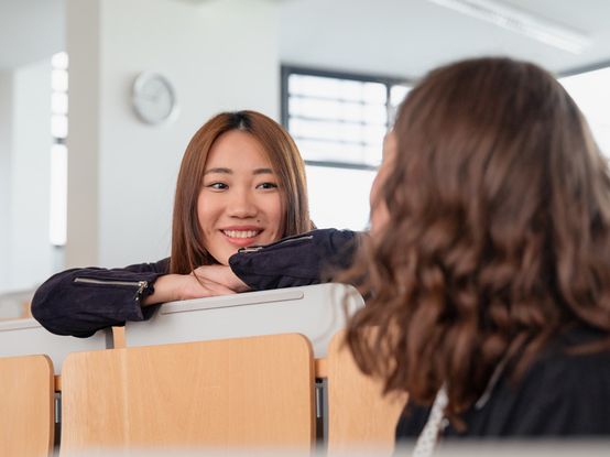 Zwei Studierende im Gespräch im Hörsaal an der Hochschule