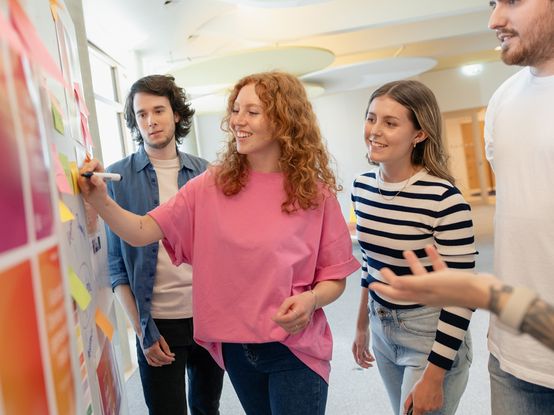 Drei dm-Studierende brainstormen mit Ausbildern am Whiteboard