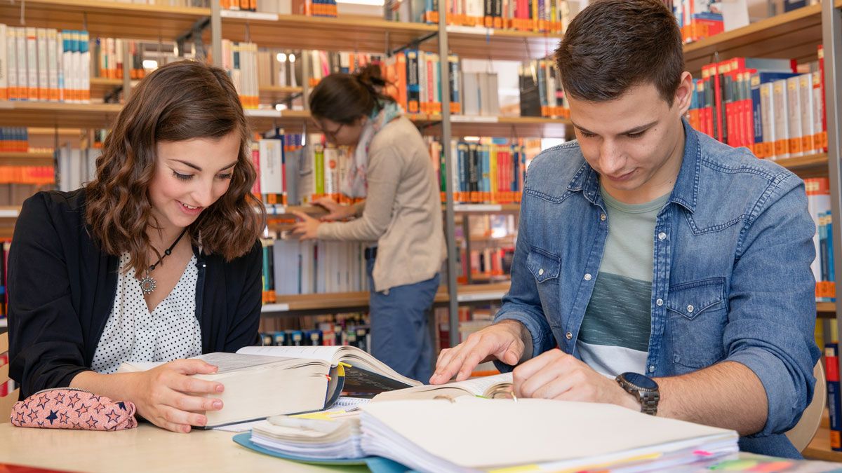 Zwei dm-Studierende lernen am Schreibtisch in Bibliothek der Hochschule