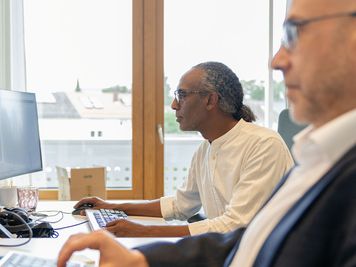 Zwei dm-Mitarbeiter arbeiten konzentriert am Computer