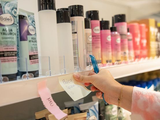 Post-it mit dem Text Balea Spülung wird auf ein Regal geklebt