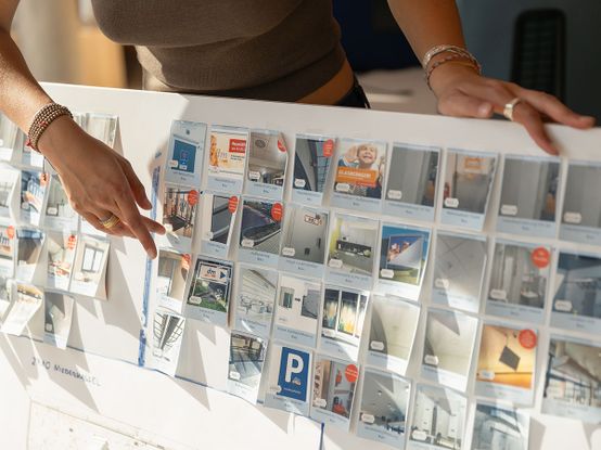 Person, die auf eine Schautafel mit Fotos von verschiedenen Baubestandteilen eines dm-Marktes zeigt.