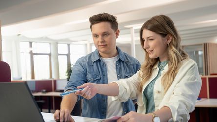 Zwei junge Menschen im Gespräch vor Laptop im dm-Unternehmenssitz