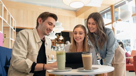 Drei junge Menschen arbeiten am Tablet in dm-Kaffebar