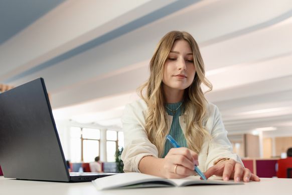 dm-Studierende arbeitet am Laptop im dm-Unternehmenssitz